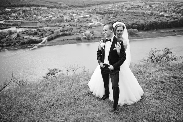 Prachtige bruidspaar op de heuvel met de rivier en mooie lan — Stockfoto