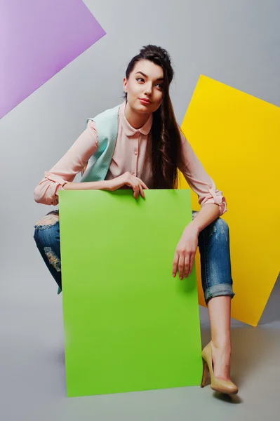 Full längd vacker flicka sitter, håller grön blank annonser — Stockfoto