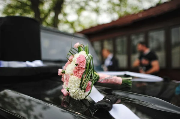 Bröllop bukett på motorhuven på bilen med stora inredning hatt — Stockfoto