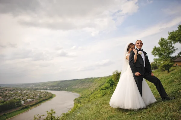 Traumhaftes Hochzeitspaar auf dem Hügel mit Fluss und wunderschönem — Stockfoto