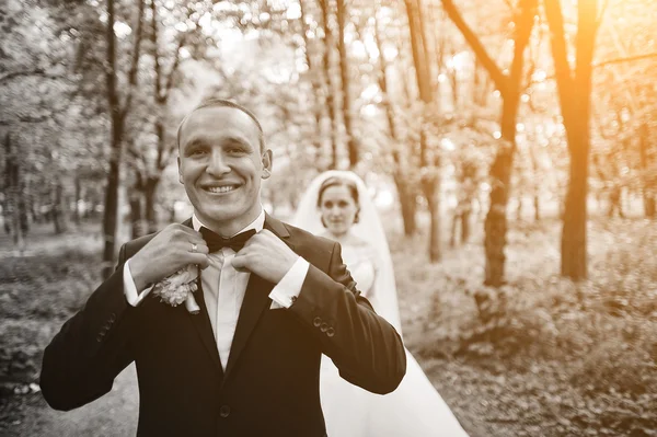 Stijl bruidegom corrigeert zijn bruid strikje achtergrond — Stockfoto
