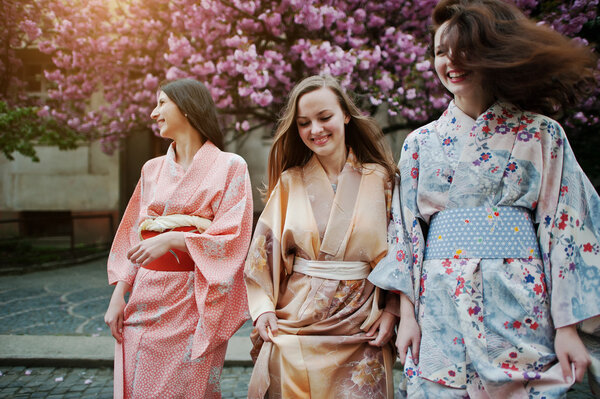 Three european girls wearing traditional japanese kimono backgro