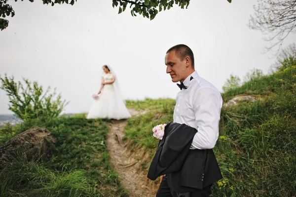 Stijlvolle bruidegom man met de jas aan kant achtergrond bruid — Stockfoto