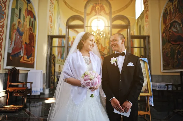 Verheugd huwelijksfeest paar verblijf in kerk en elkaar gekeken met zon — Stockfoto