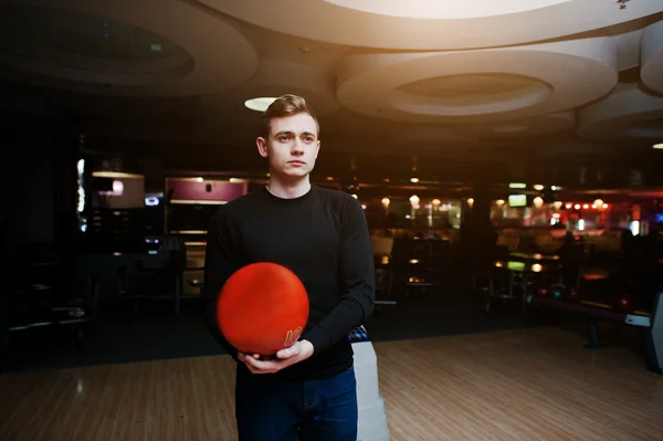Молодой человек держит шар для боулинга, стоящий напротив боулинга. — стоковое фото