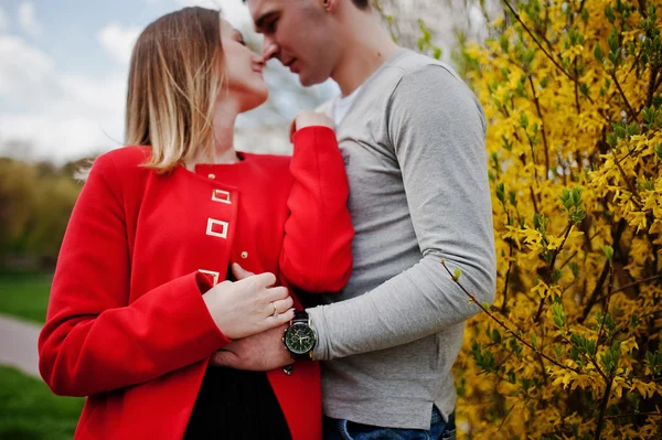 Liebendes Paar, das sich in der Nähe eines Busches mit gelben Blüten umarmt, aus nächster Nähe — Stockfoto