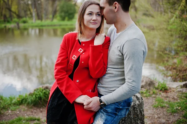 Feliz pareja amorosa sentada y abrazada en piedra en el parque backgro — Foto de Stock