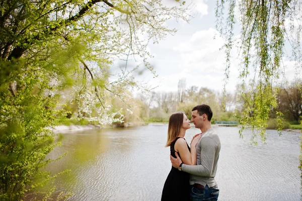 Giovane coppia innamorata soggiorno all'aperto vicino lago con salici — Foto Stock
