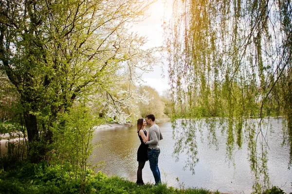 Young couple in love outdoor stay near lake with willow trees — Stock Photo, Image