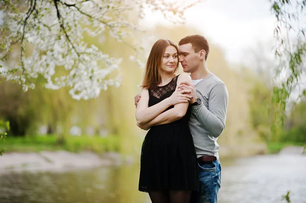 Pareja joven enamorada al aire libre lago de fondo con árbol de flores —  Fotos de Stock