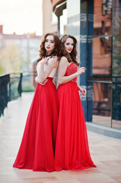 Retrato de duas meninas na moda em vestido de noite vermelho bac posado — Fotografia de Stock