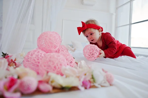 Malé roztomilé děvče v červených šatech hrají na velké bílé posteli — Stock fotografie
