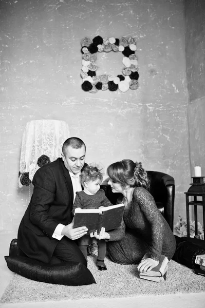 Šťastná rodina s dcerou číst staré knize na pozadí koberce — Stock fotografie