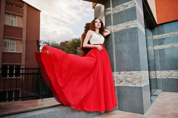 Портрет модной девушки в красном вечернем платье позировал backgrou — стоковое фото