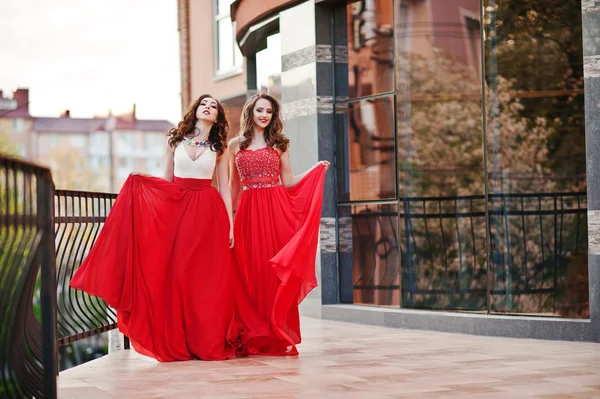 Retrato de dos chicas de moda en vestido de noche rojo posado bac — Foto de Stock