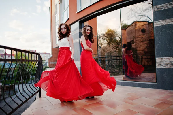 Retrato de duas meninas na moda em vestido de noite vermelho bac posado — Fotografia de Stock