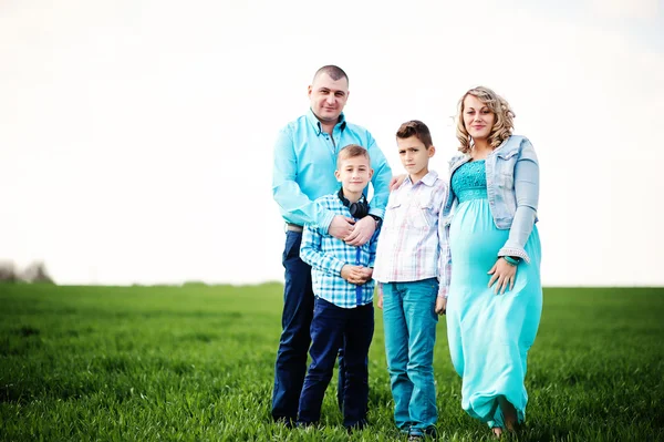 Glückliche schwangere Familie mit zwei Söhnen, gekleidet in ein türkisfarbenes Blutgerinnsel — Stockfoto