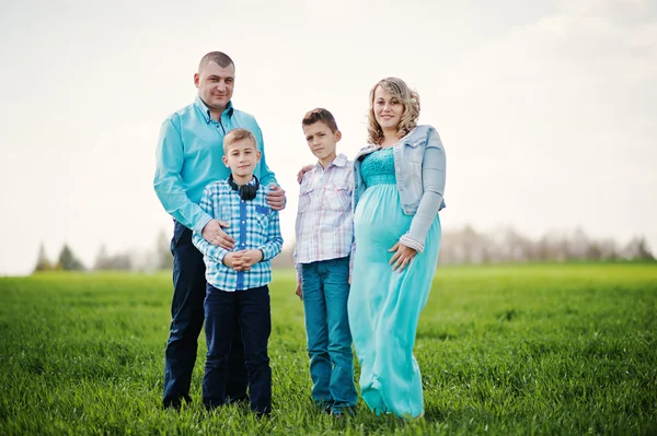 Glückliche schwangere Familie mit zwei Söhnen, gekleidet in ein türkisfarbenes Blutgerinnsel — Stockfoto