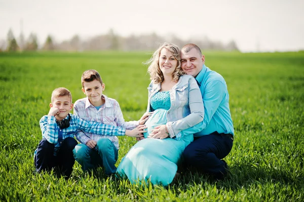 Família grávida feliz com dois filhos, vestida com um coágulo turquesa — Fotografia de Stock