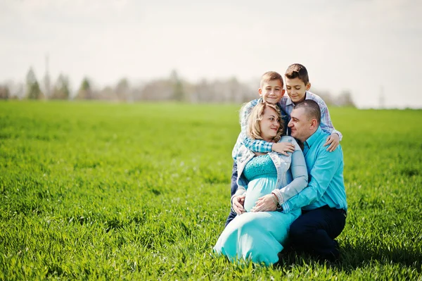 Família grávida feliz com dois filhos, vestida com um coágulo turquesa — Fotografia de Stock