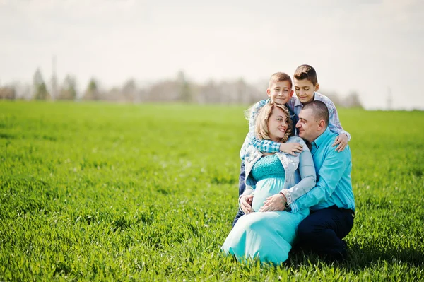 Família grávida feliz com dois filhos, vestida com um coágulo turquesa — Fotografia de Stock