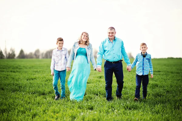 Šťastná těhotná rodina se dvěma syny, oblečená v tyrkysové sraženinu — Stock fotografie