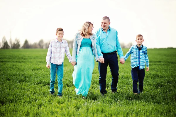 Glückliche schwangere Familie mit zwei Söhnen, gekleidet in ein türkisfarbenes Blutgerinnsel — Stockfoto