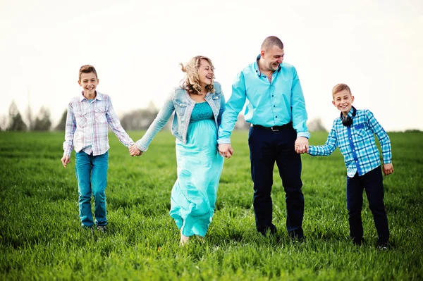 Família grávida feliz com dois filhos, vestida com um coágulo turquesa — Fotografia de Stock