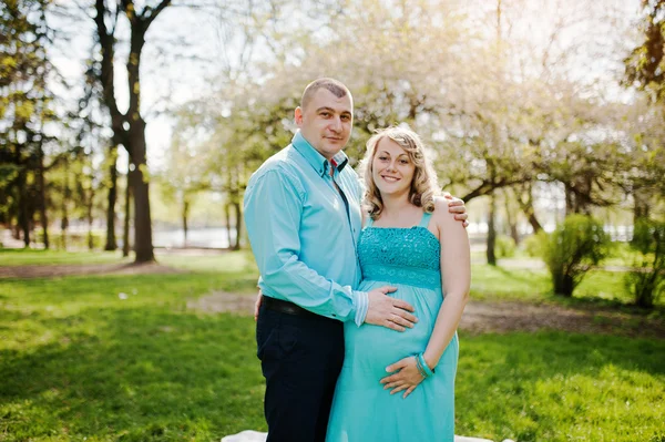 Feliz embarazada pareja abrazando en naturaleza fondo primavera blosso —  Fotos de Stock