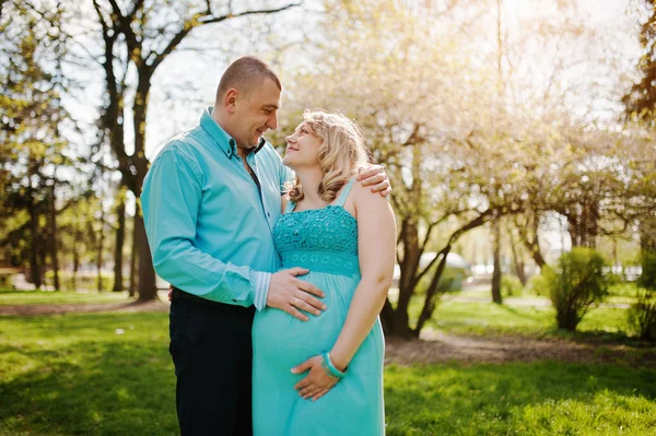 Feliz grávida casal abraçando na natureza fundo primavera blosso — Fotografia de Stock