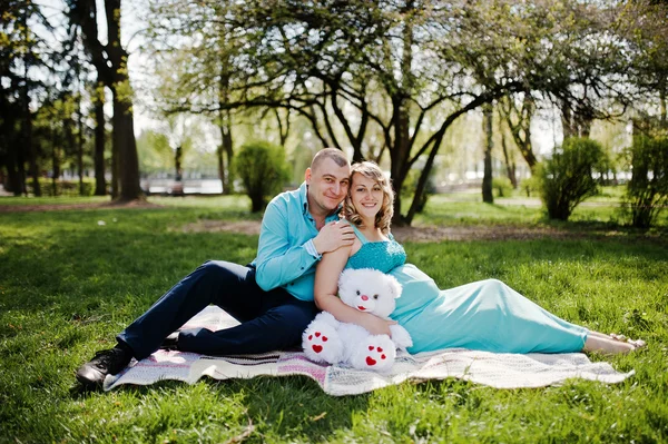 Feliz pareja embarazada abrazando y sentado en el fondo a cuadros sp —  Fotos de Stock