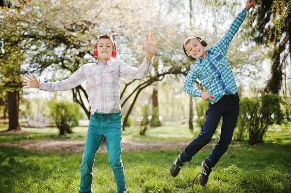 Two brother boy with headphones having fun and jump in air on pa — Stock Photo, Image