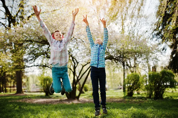 Dos hermano chico con auriculares divertirse y saltar en el aire en pa — Foto de Stock