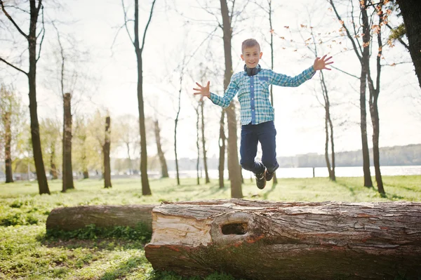 Lilla roliga pojke hoppa Froom träd stubbe på Park — Stockfoto