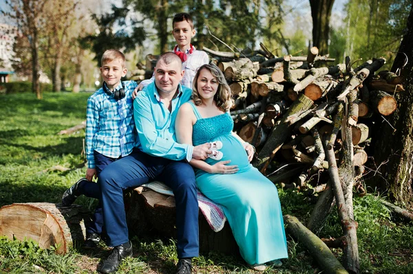 Szczęśliwa rodzina w ciąży z dwoma synami, ubrana w turkusowy skrzep — Zdjęcie stockowe