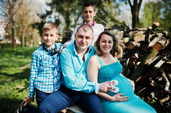 Šťastná těhotná rodina se dvěma syny, oblečená v tyrkysové sraženinu — Stock fotografie