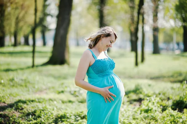 Portrait de femme enceinte heureuse vêtue d'une robe turquoise à — Photo