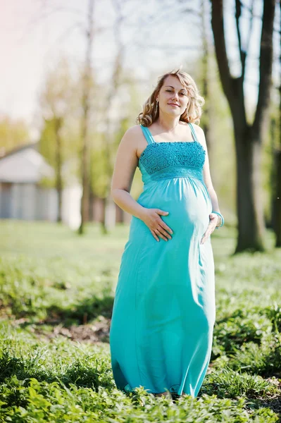 Portrait of happy pregnant woman dressed in a turquoise dress at — Stock Photo, Image