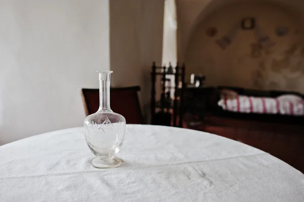 Decantador vintage velho em uma mesa redonda com um backgrou de toalha de mesa — Fotografia de Stock