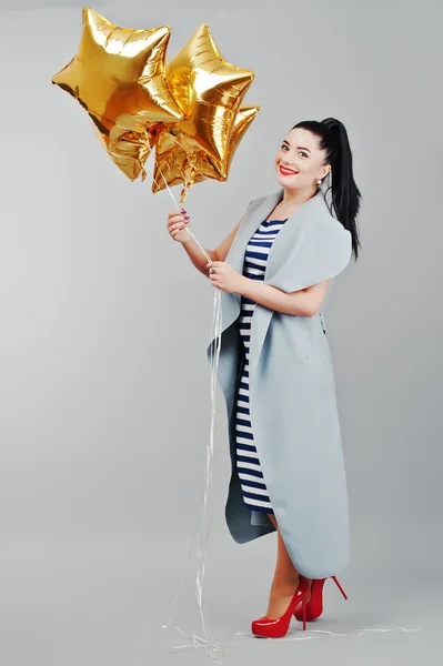 Young smiled woman with gold balloons at hands background gray i — Stock Photo, Image