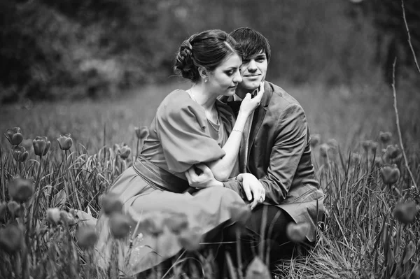 Pareja abrazándose en el amor en el campo de tulipanes rojo. Hombre con estilo en terciopelo — Foto de Stock