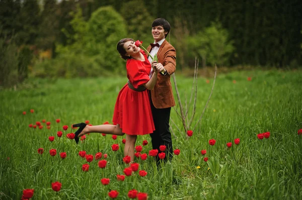 Couple hugging in love at red tulip field. Stylish man at velvet — Stock Photo, Image