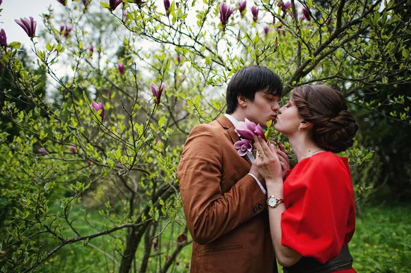 マグノリアの木の近くで恋に抱きしめるカップル。ベルベットでスタイリッシュな男 — ストック写真