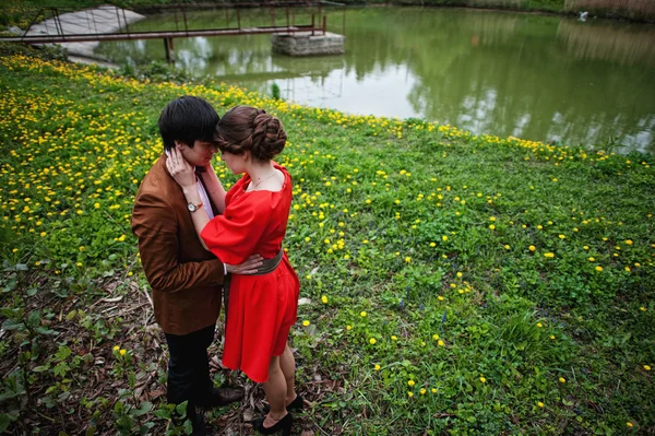 Pareja abrazándose en el amor en el campo de flores amarillas cerca del lago y pon —  Fotos de Stock