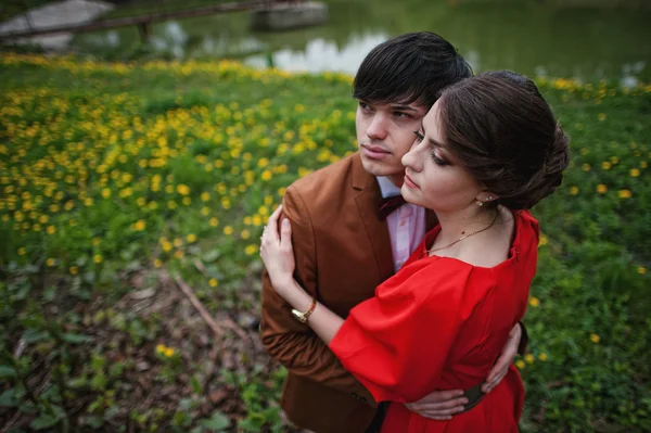 Casal abraçando no amor no campo de flores amarelas perto do lago e do pon — Fotografia de Stock