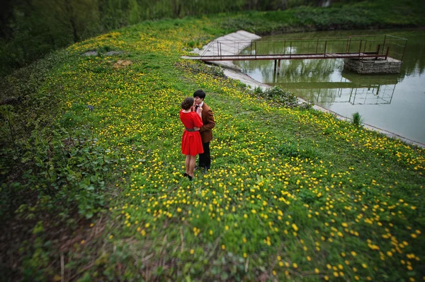 Couple hugging in love at yellow flowers field near lake and pon — Stock Photo, Image