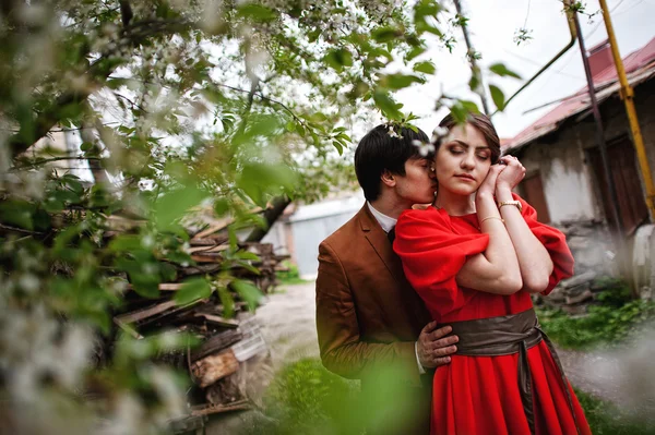 Pareja abrazándose en el amor cerca de los árboles florecientes jardín. Hombre con estilo a — Foto de Stock