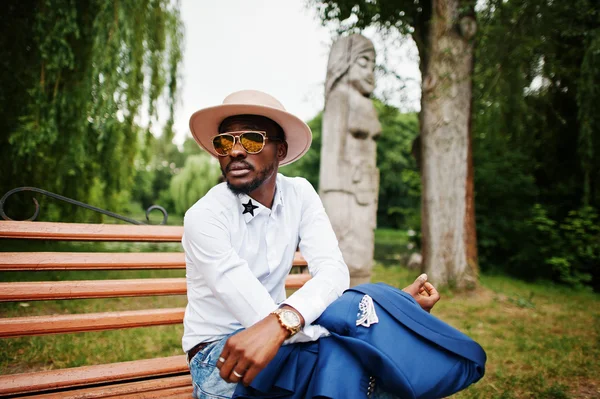 Gazdag fekete ember ül a padon arany napszemüveg és kalap — Stock Fotó