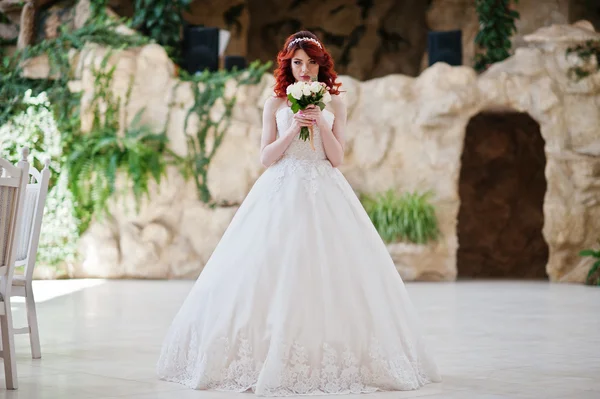 Charmante mariée aux cheveux roux avec bouquet de mariage à portée de main posé à — Photo