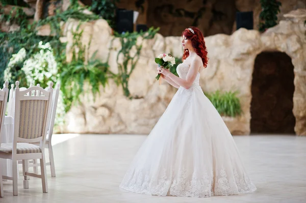 Charmante mariée aux cheveux roux avec bouquet de mariage à portée de main posé à — Photo